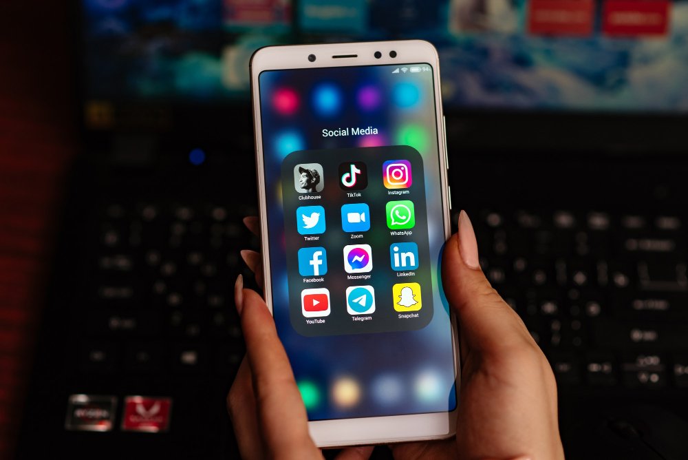 Hands holding smartphone displaying social media apps folder with Instagram, TikTok, WhatsApp, Facebook, Twitter, YouTube and other popular apps that use Android app cache for faster loading and performance.