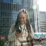 Young professional checking 929 NYC area code phone number on mobile device in Manhattan business district